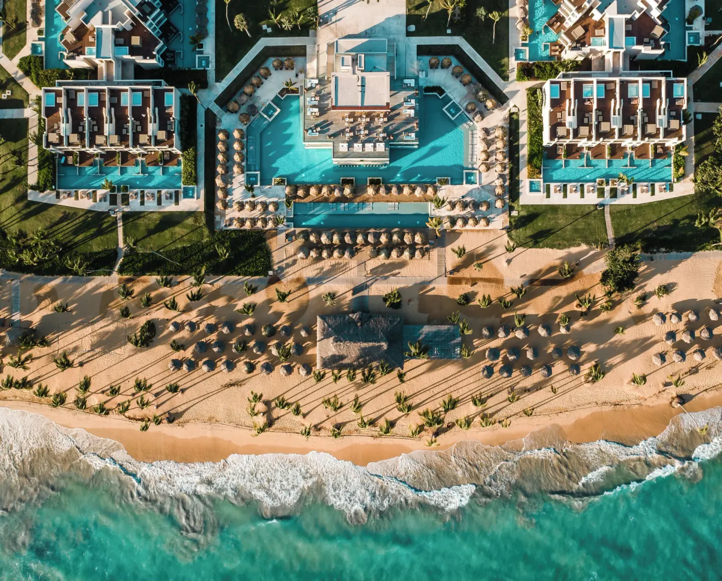 Aerial view of pools, beach, and shoreline at Excellence El Carmen.