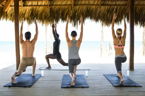 Beachfront yoga class under a thatched pavilion at Excellence El Carmen.