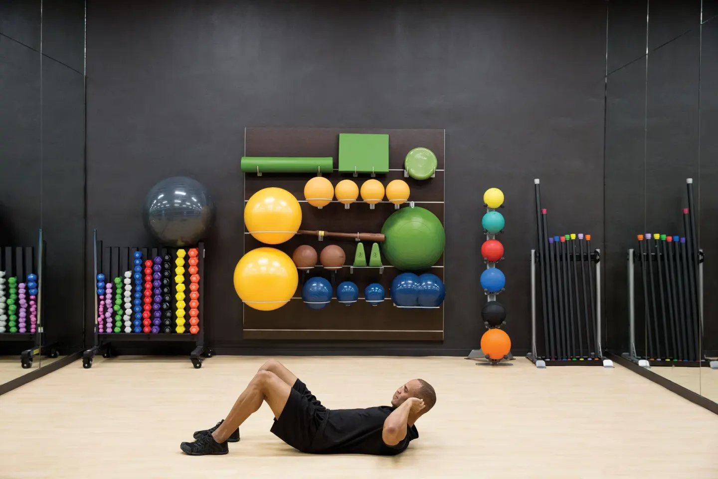 Fitness studio with exercise balls, weights, and a guest doing crunches at Excellence El Carmen.