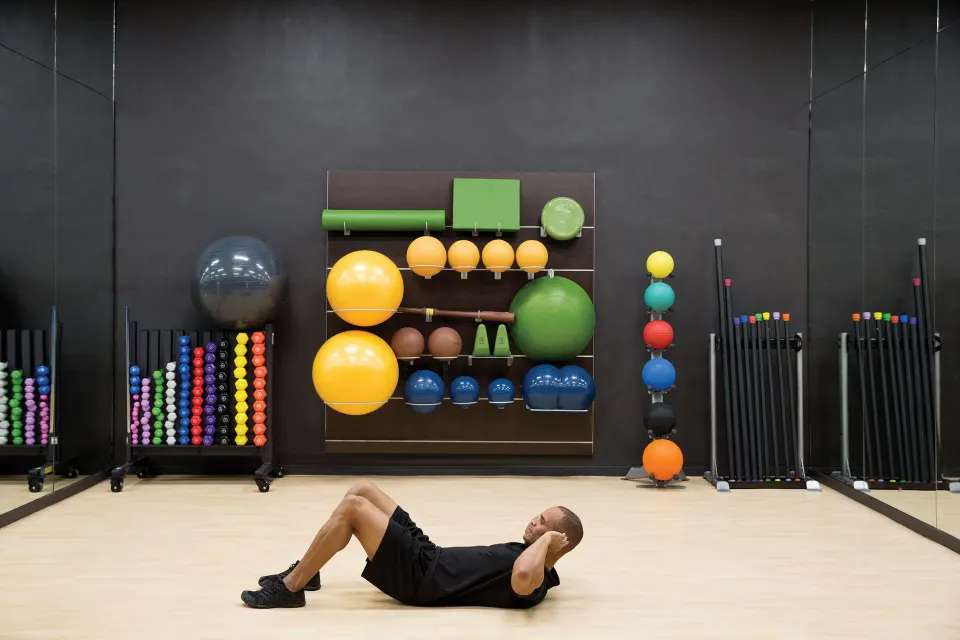 Fitness studio with exercise balls, weights, and a guest doing crunches at Excellence El Carmen.