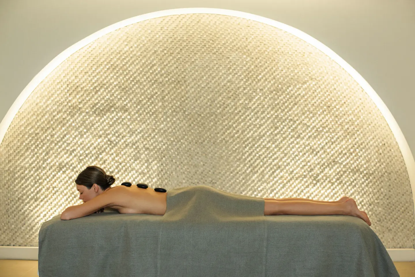 Guest receiving a hot stone treatment on a spa table at Excellence El Carmen.