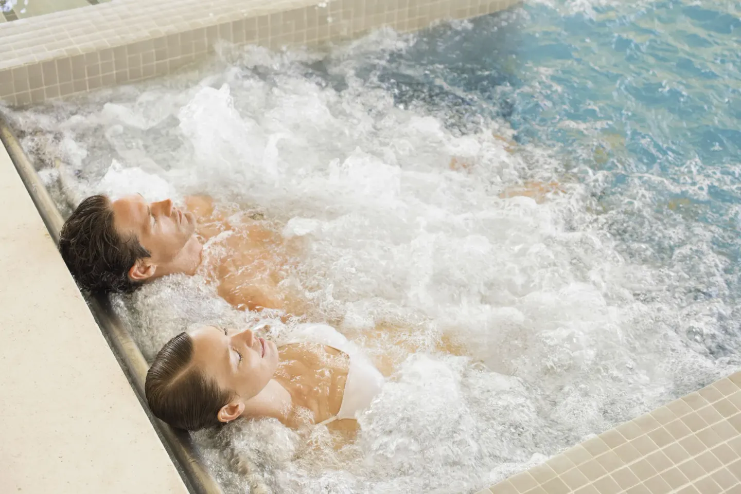 Couple relaxing in a bubbling hydrotherapy pool at Excellence El Carmen.