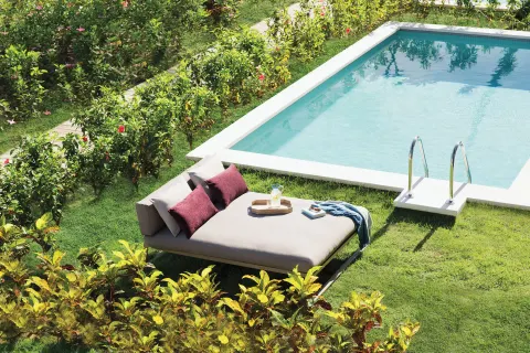 Private pool patio with daybed, pillows, and garden hedges at Excellence El Carmen.
