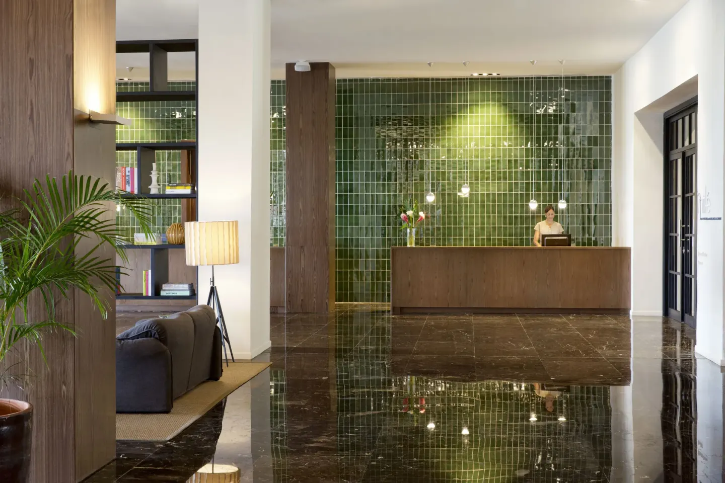 Reception desk with green tile wall and glossy floors at Excellence El Carmen.