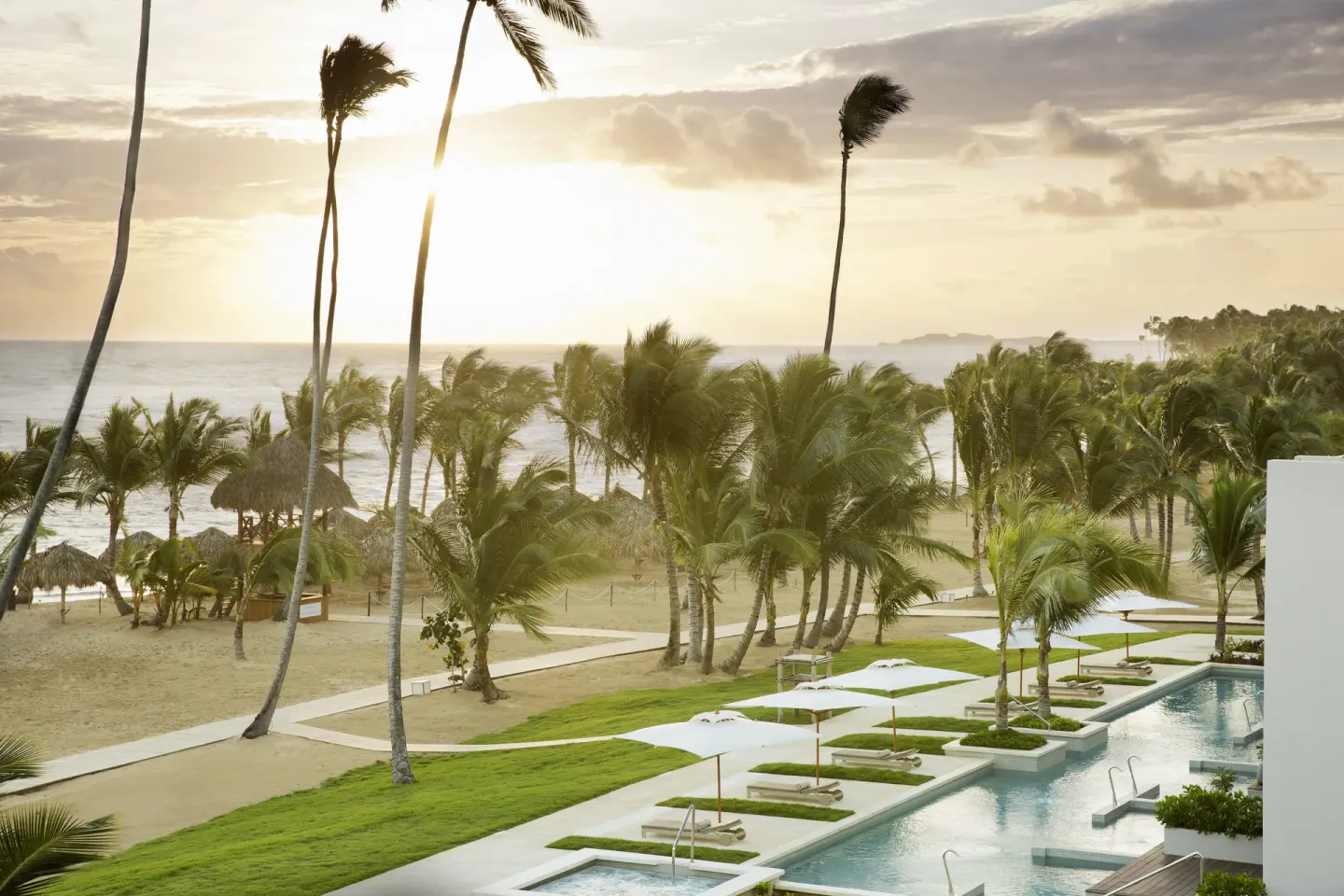Sunrise over the beach, palms, and pool at Excellence El Carmen.