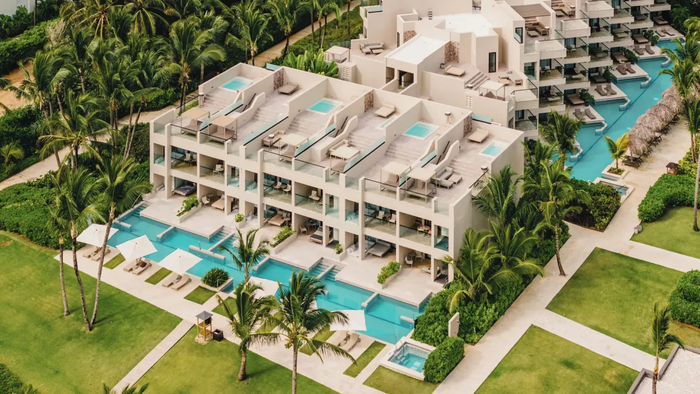 Aerial view of swim-up suites, rooftop terraces, and palms at Excellence El Carmen.