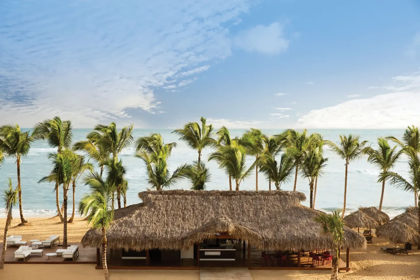Thatched beachfront pavilion, palms, loungers, and ocean view at Excellence El Carmen.