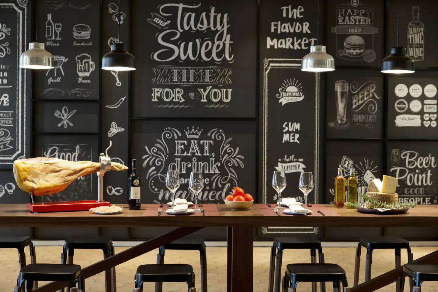 A tapas-style counter with cured ham, wine, cheese, and chalkboard art at Excellence El Carmen.