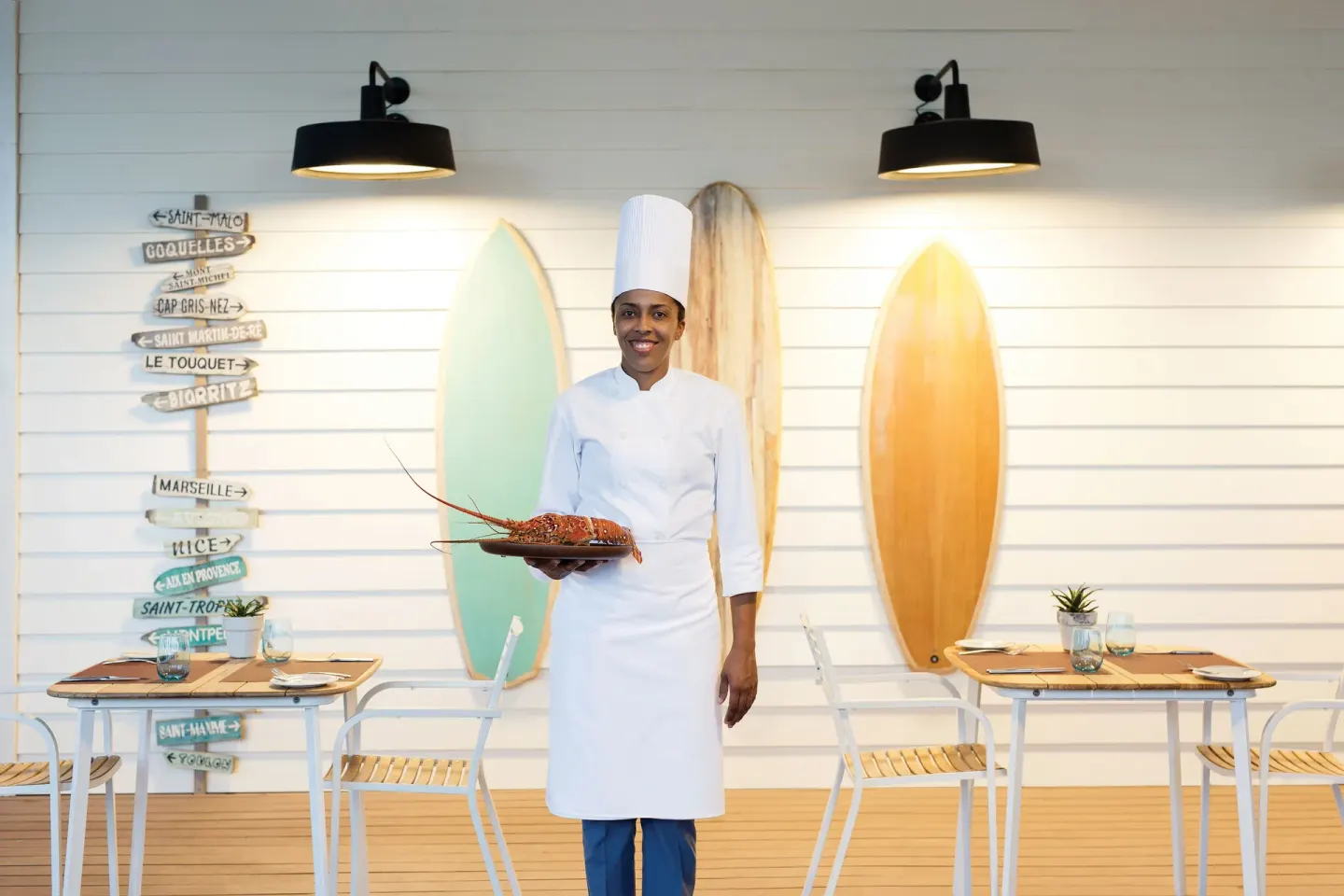 A chef presents a lobster in a surf-themed restaurant at Excellence El Carmen.