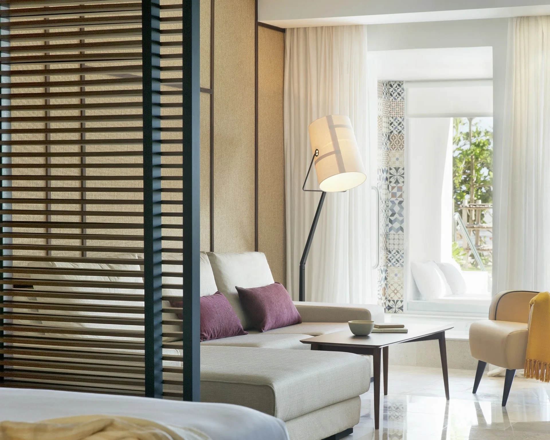 Suite lounge with sofa, floor lamp, chair, and bed edge at Excellence El Carmen.