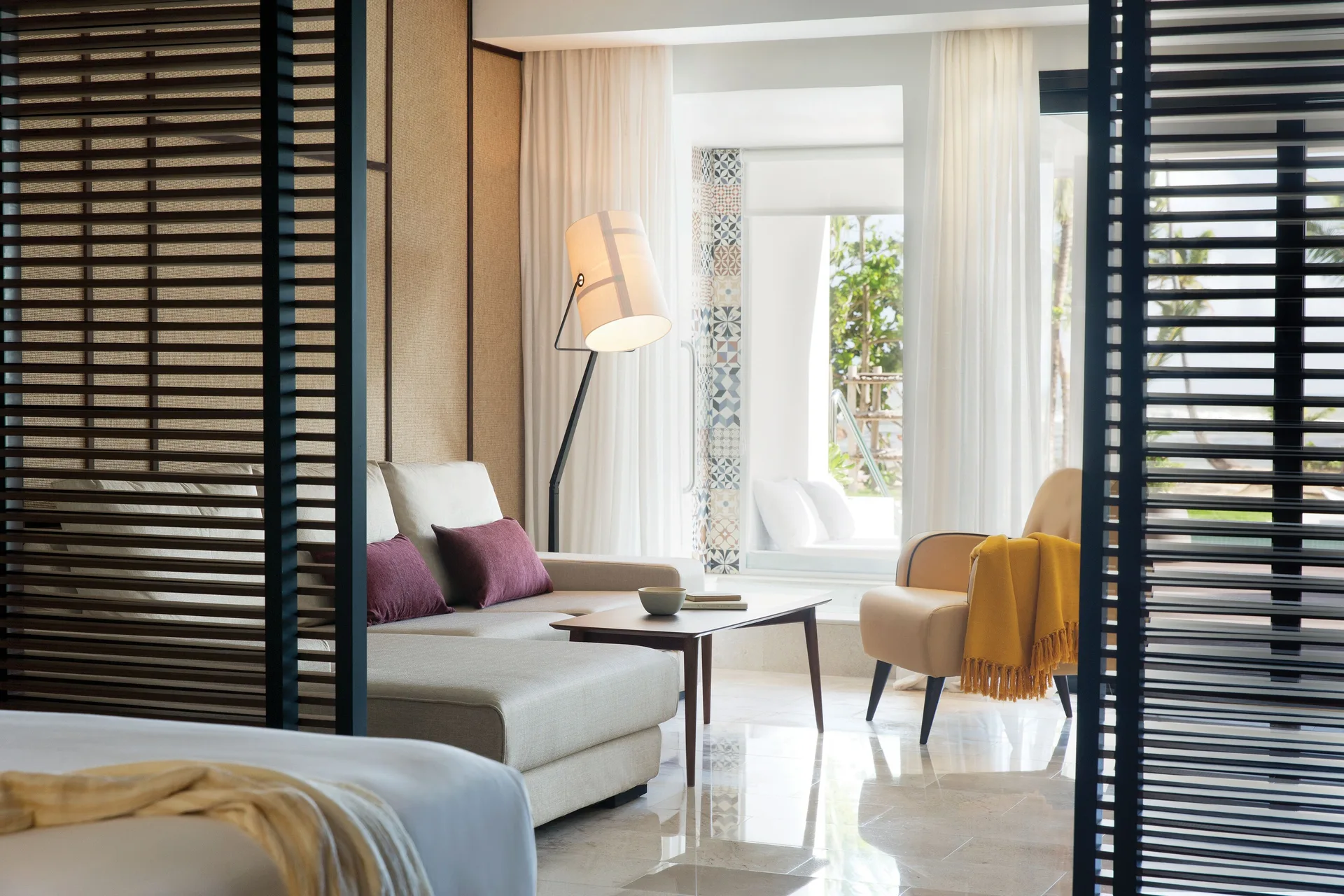 Sitting area with sofa, lounge chair, and partial bed view at Excellence El Carmen.
