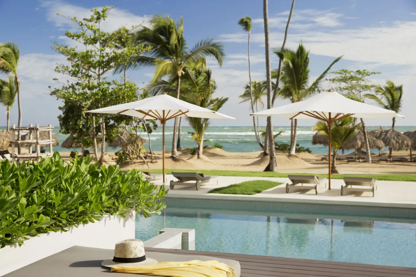 Swim-up terrace pool with beach umbrellas and ocean beyond at Excellence El Carmen.