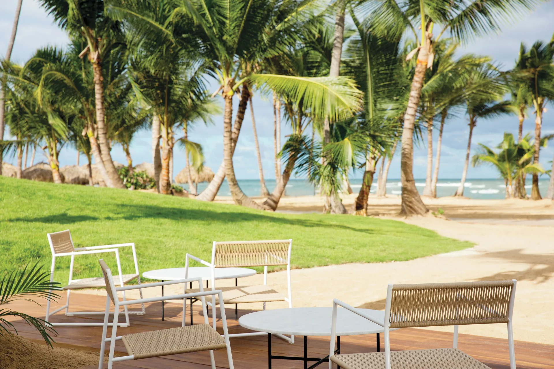 Private deck seating by palms and beach at Excellence El Carmen