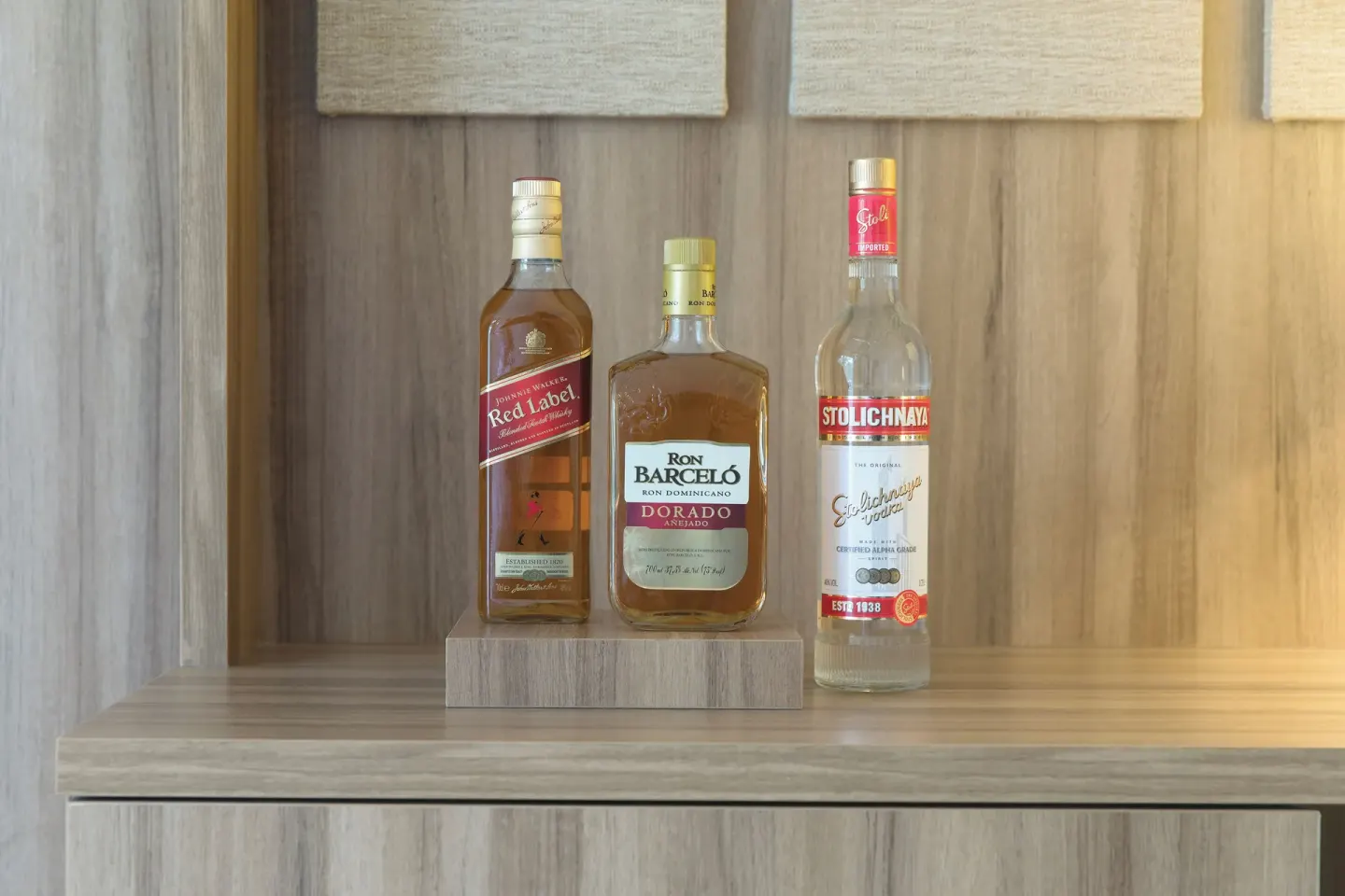 Junior Suite Pool View in-room liquor bottles on a wood shelf at Excellence El Carmen.