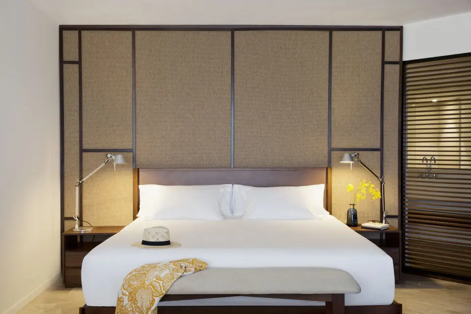 Junior Suite Pool View king bed with bench and bedside lamps at Excellence El Carmen.