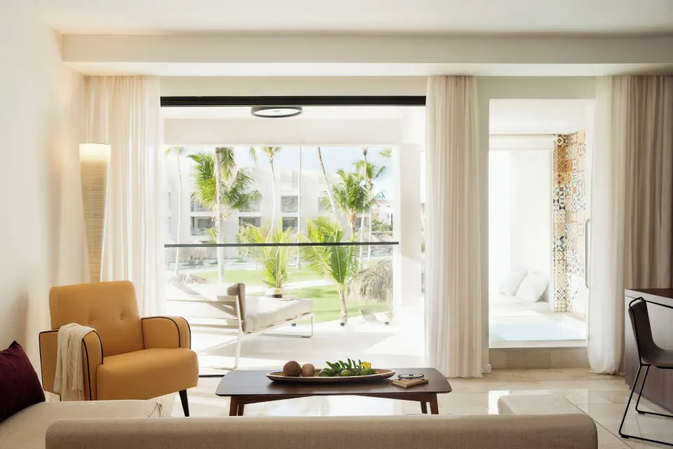 Junior Suite Pool View sitting area and balcony with palms at Excellence El Carmen.