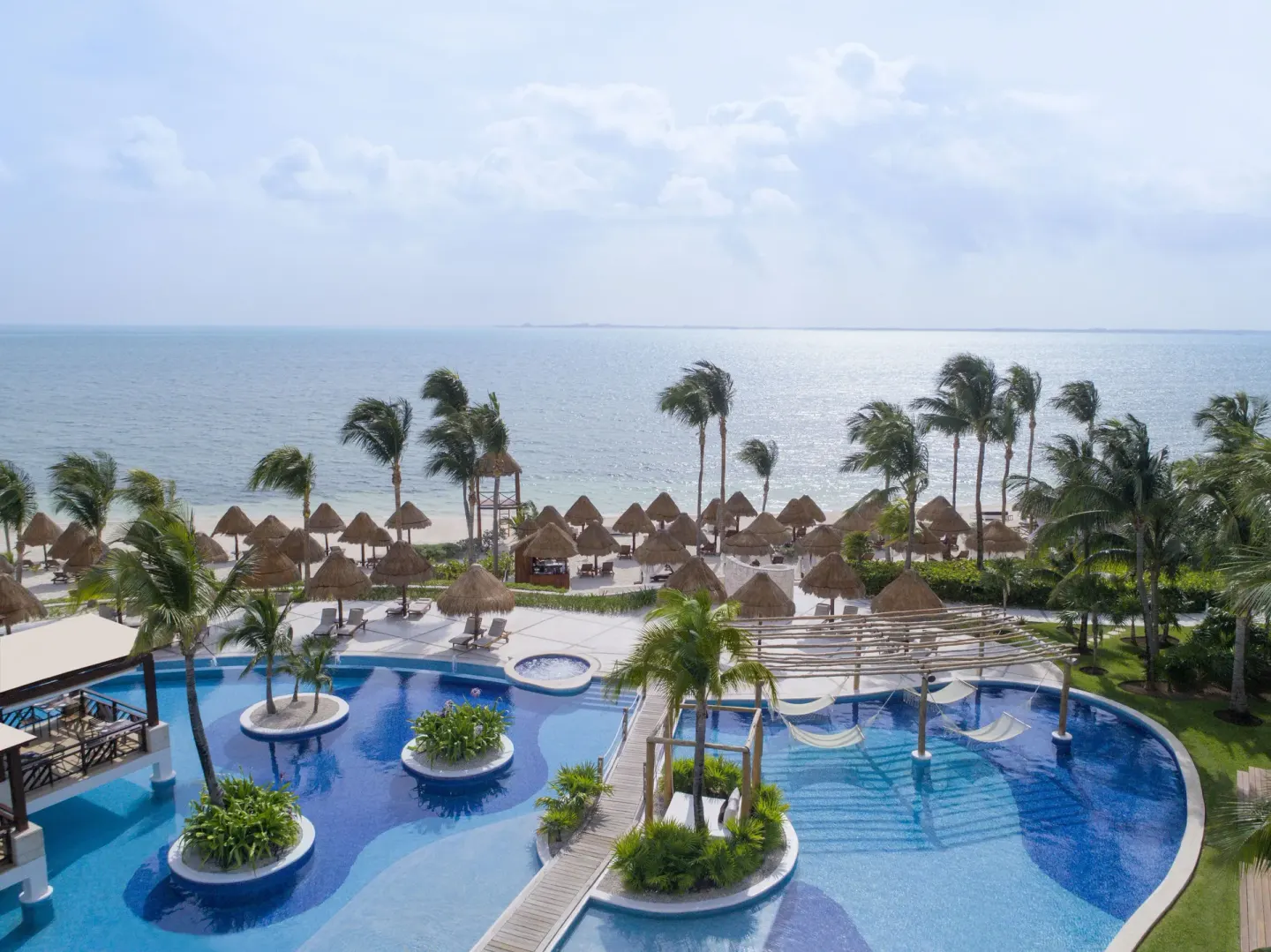 Aerial view of the resort pool, beach palapas and ocean at Excellence Playa Mujeres.