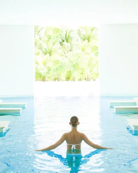 Guest standing in a bright indoor pool at Excellence Playa Mujeres.