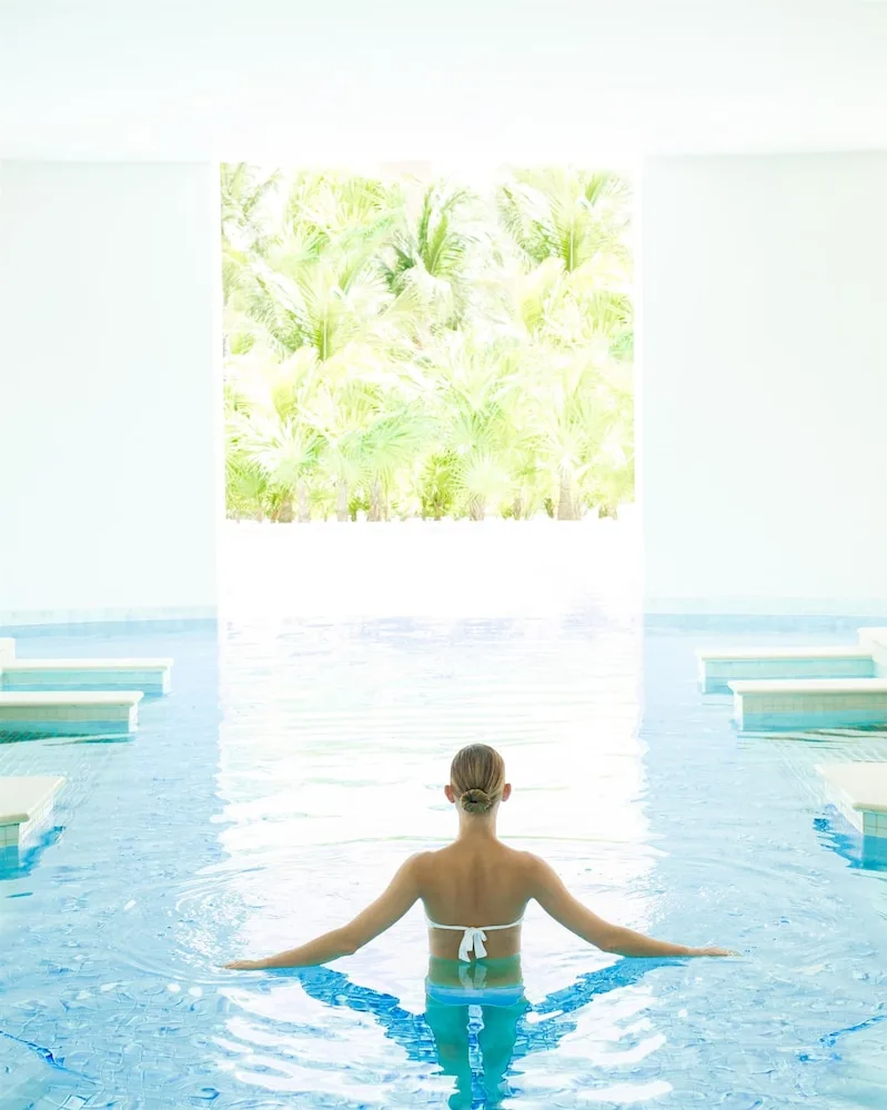 Guest standing in a bright indoor pool at Excellence Playa Mujeres.