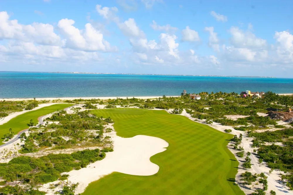 Aerial view of a golf course beside the beach and sea at Excellence Playa Mujeres.