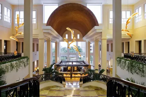 Grand lobby staircase and bar under a vaulted ceiling at Excellence Playa Mujeres.