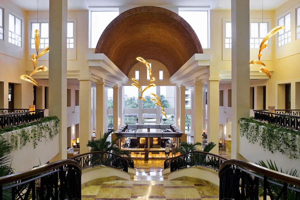 Grand lobby staircase and bar under a vaulted ceiling at Excellence Playa Mujeres.