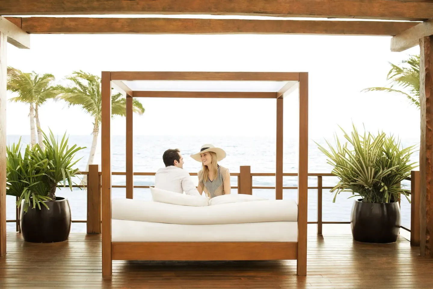 Couple relaxing on an oceanfront daybed at Excellence Playa Mujeres.