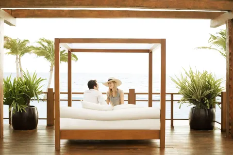 Couple relaxing on an oceanfront daybed at Excellence Playa Mujeres.