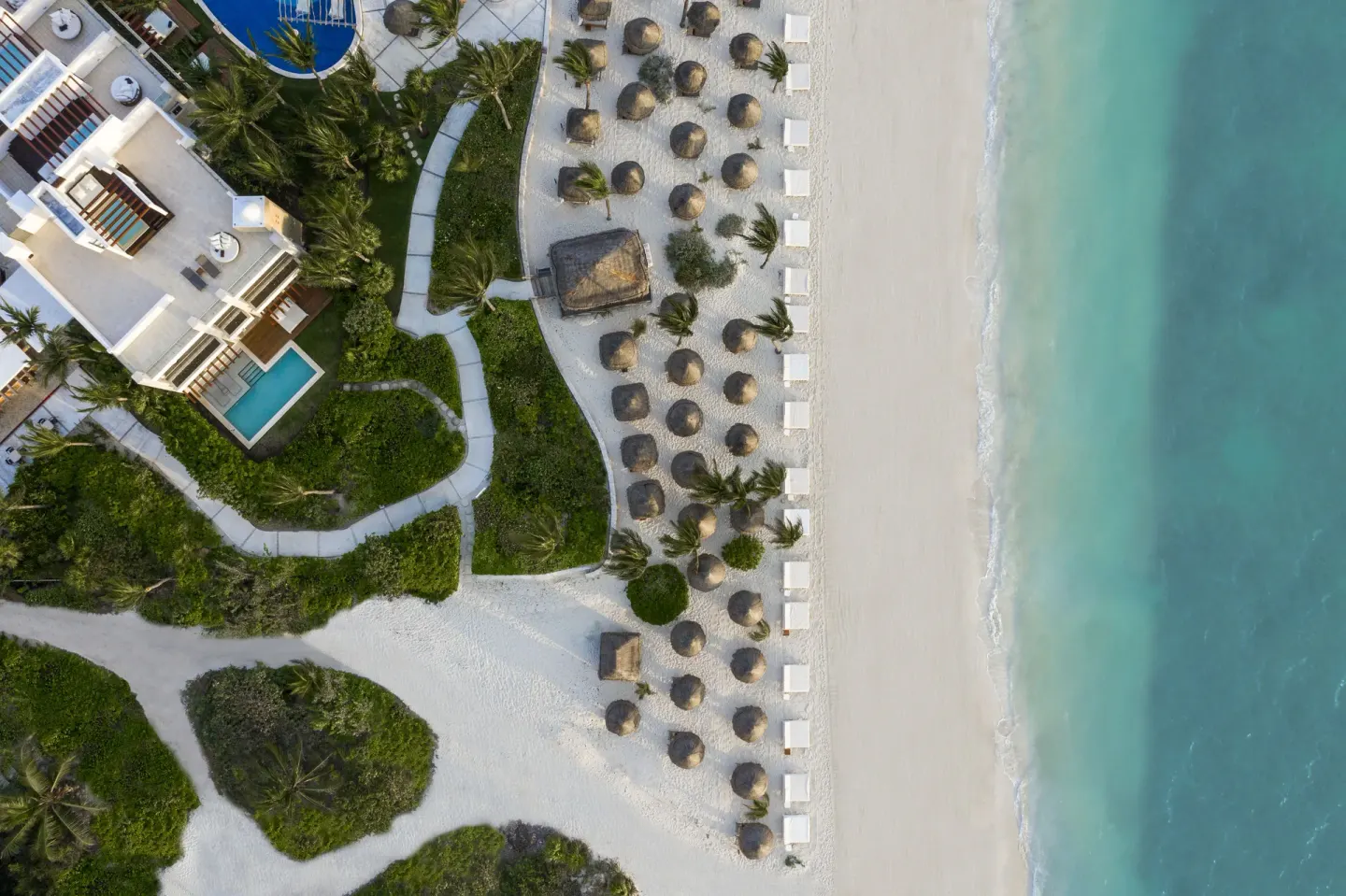 Overhead view of the beach, loungers, palapas, and turquoise water at Excellence Playa Mujeres.