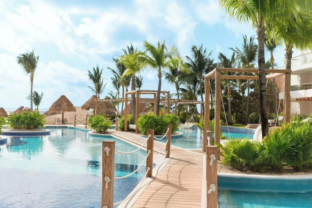 Pool bridge, hammocks and palm landscaping at Excellence Playa Mujeres.