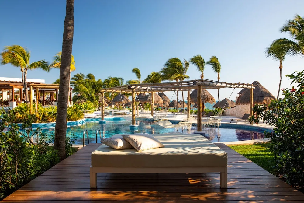 Poolside daybed, hammocks, and palapas near the beach at Excellence Playa Mujeres.