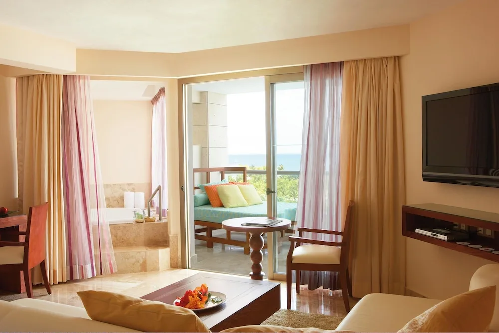 Suite living area with balcony daybed and ocean view at Excellence Playa Mujeres.