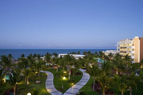 Twilight view of gardens, paths, and oceanfront buildings at Excellence Playa Mujeres.