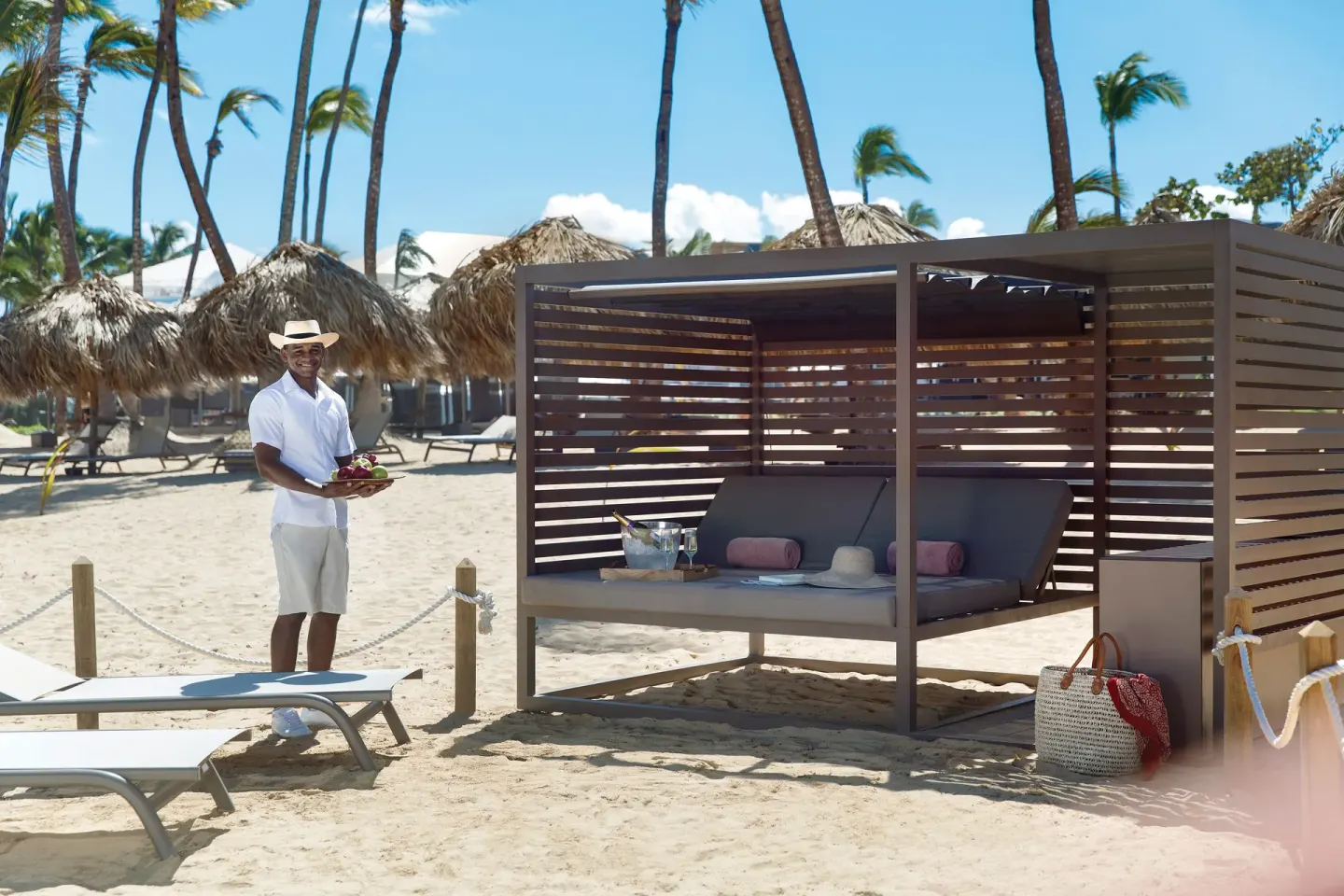 Beach cabana with a staff member holding fruit at Excellence Punta Cana.