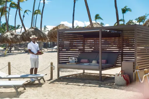 Beach cabana with a staff member holding fruit at Excellence Punta Cana.