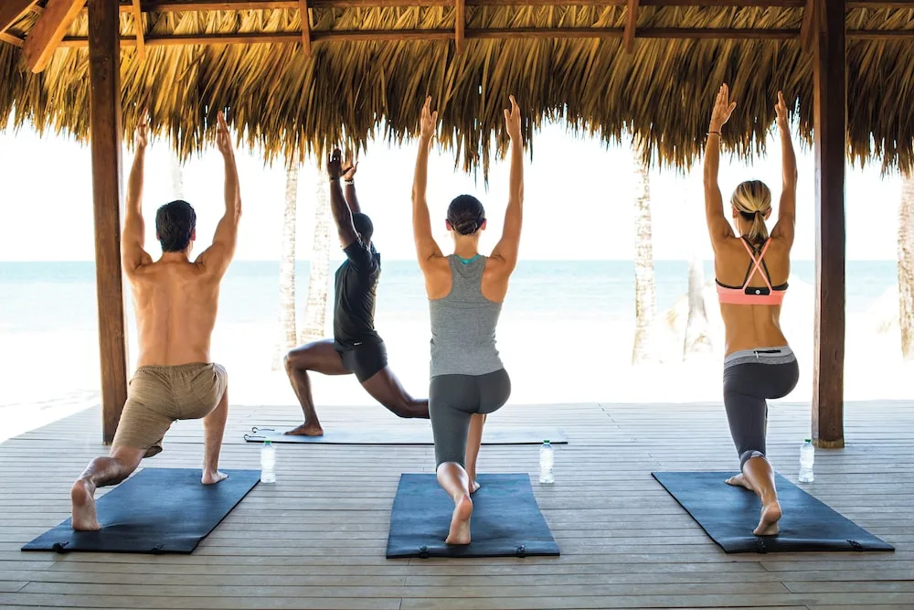 Beachfront yoga class under a thatched pavilion at Excellence Punta Cana.