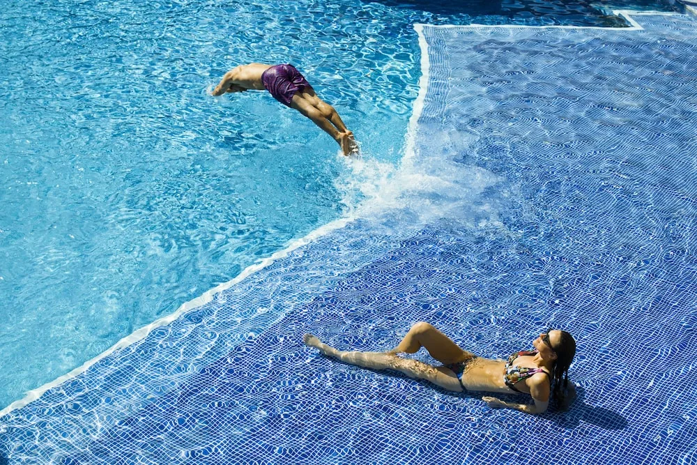 Guests enjoy a blue tiled swimming pool at Excellence Punta Cana.