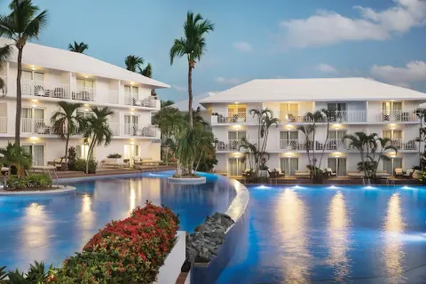 Evening pool bordered by white guest-room buildings at Excellence Punta Cana.