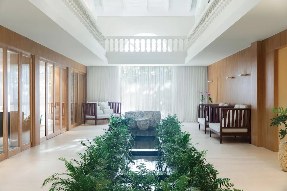 A bright lounge with plants, seating, and a narrow water feature at Excellence Punta Cana.