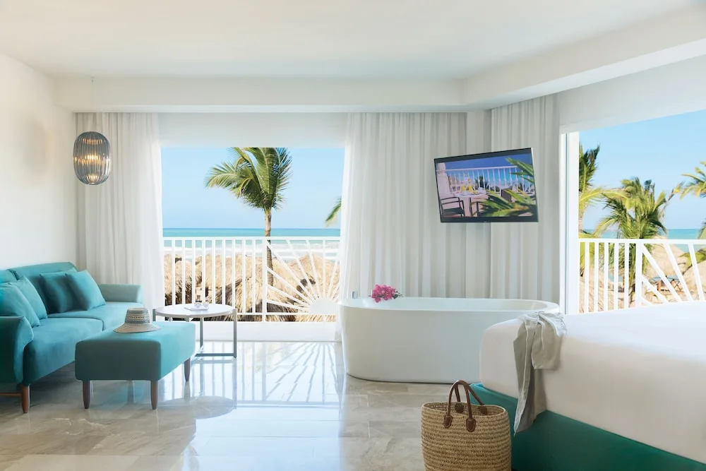 Ocean-view guest room with king bed, sofa, tub and balcony at Excellence Punta Cana.