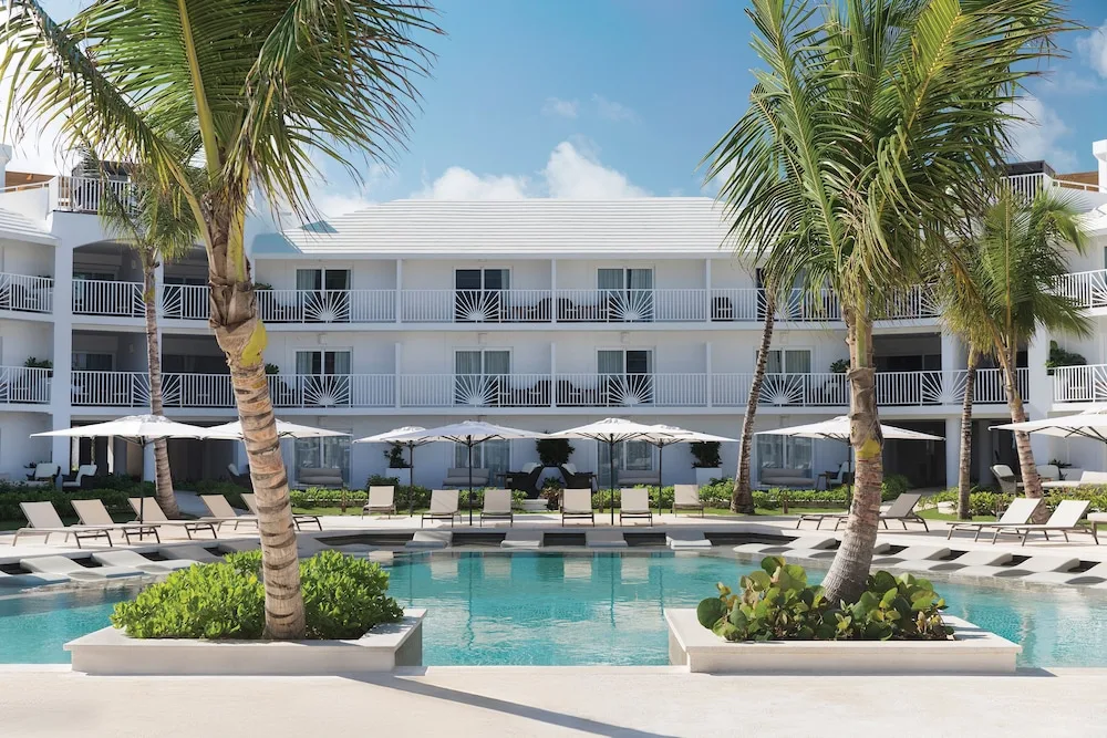 A palm-lined pool and white guest-room building at Excellence Punta Cana.