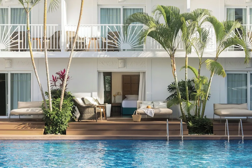 Poolside guest room terrace with loungers and balcony above at Excellence Punta Cana.