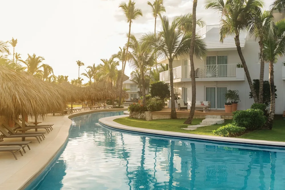 Swim-up pool beside white guest buildings and palm trees at Excellence Punta Cana.