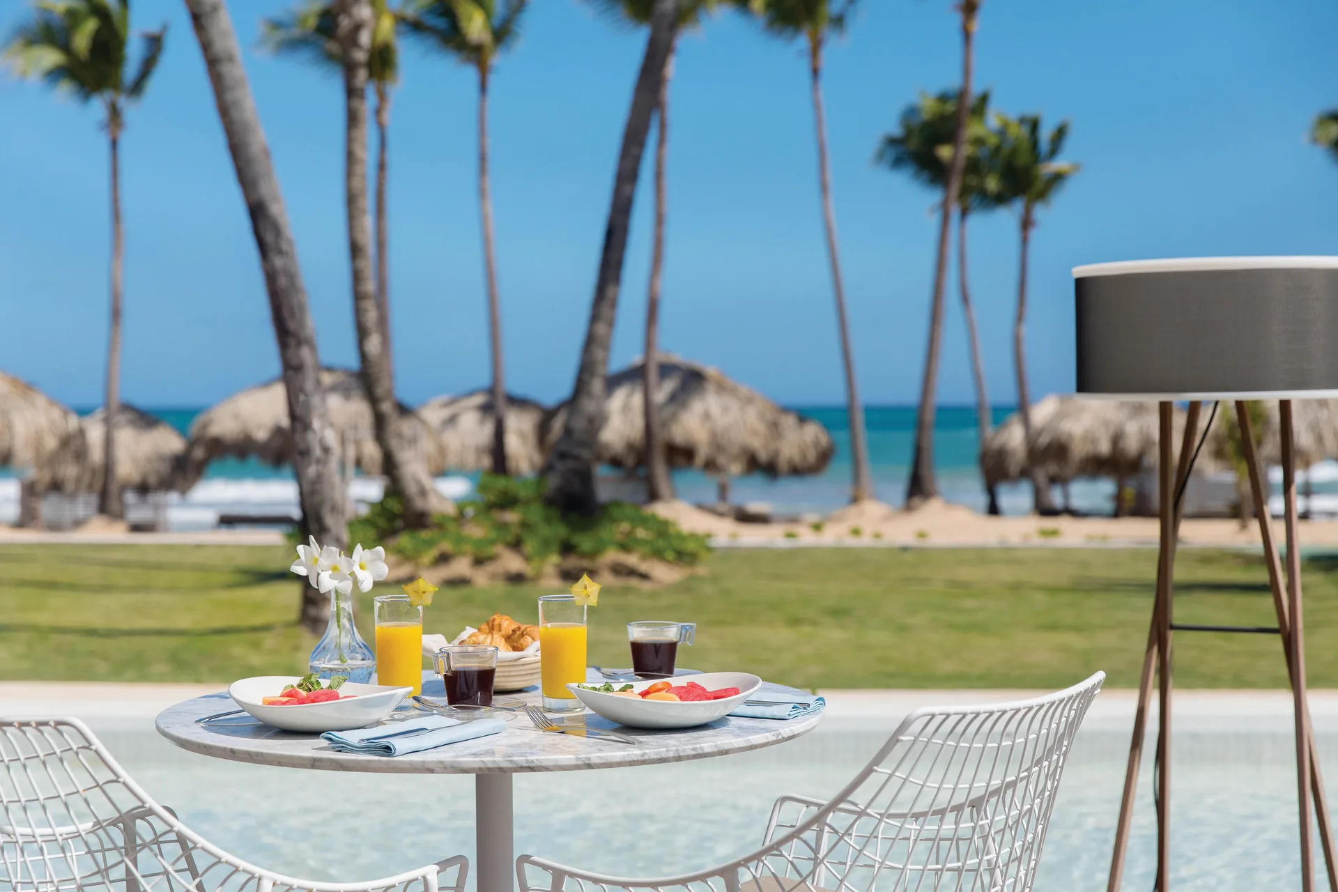 Breakfast table by the pool with beach palms at Excellence Punta Cana.