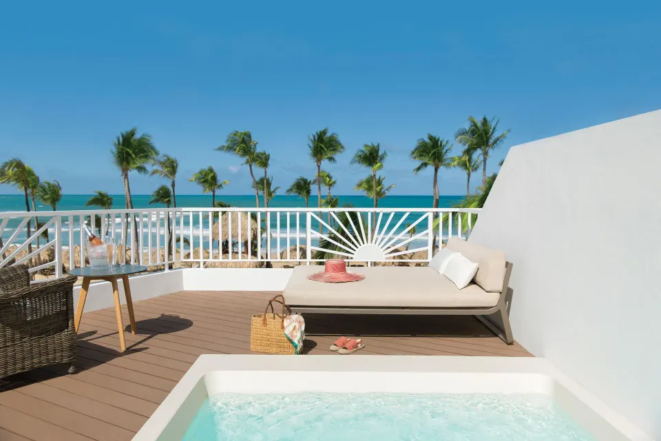 Oceanfront terrace with plunge tub at Excellence Punta Cana, overlooking palms and sea.