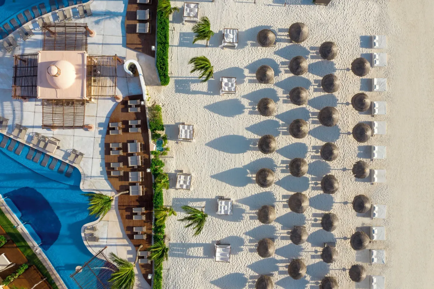 Aerial view of the pool deck and beach palapas at Excellence Riviera Cancun.