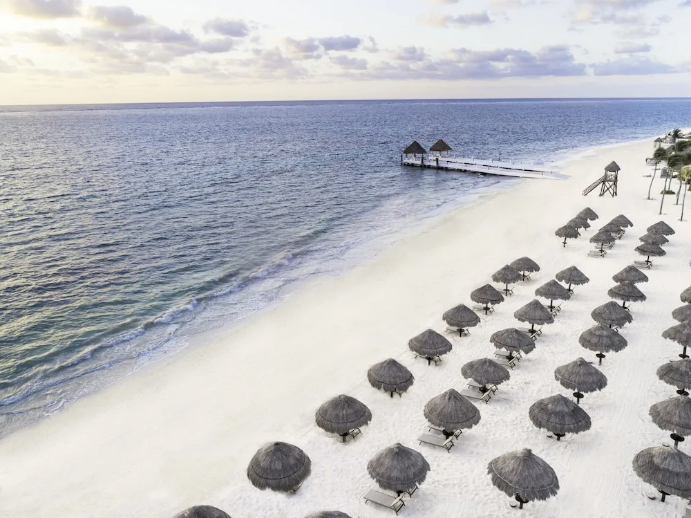 Aerial beach view with palapas and pier at Excellence Riviera Cancun.