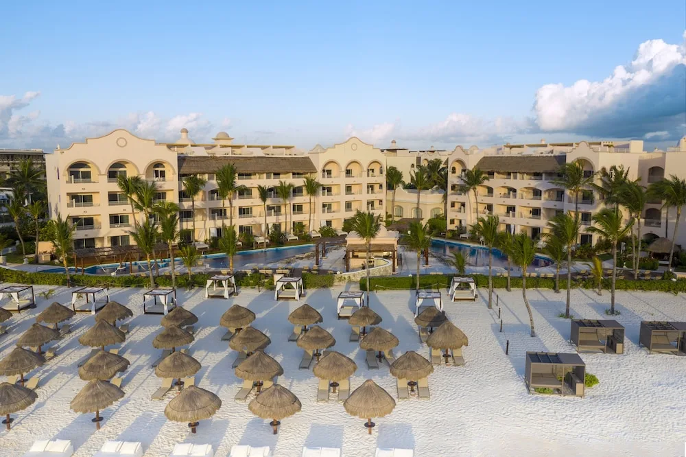 Beach palapas, pools, and resort buildings at Excellence Riviera Cancun.