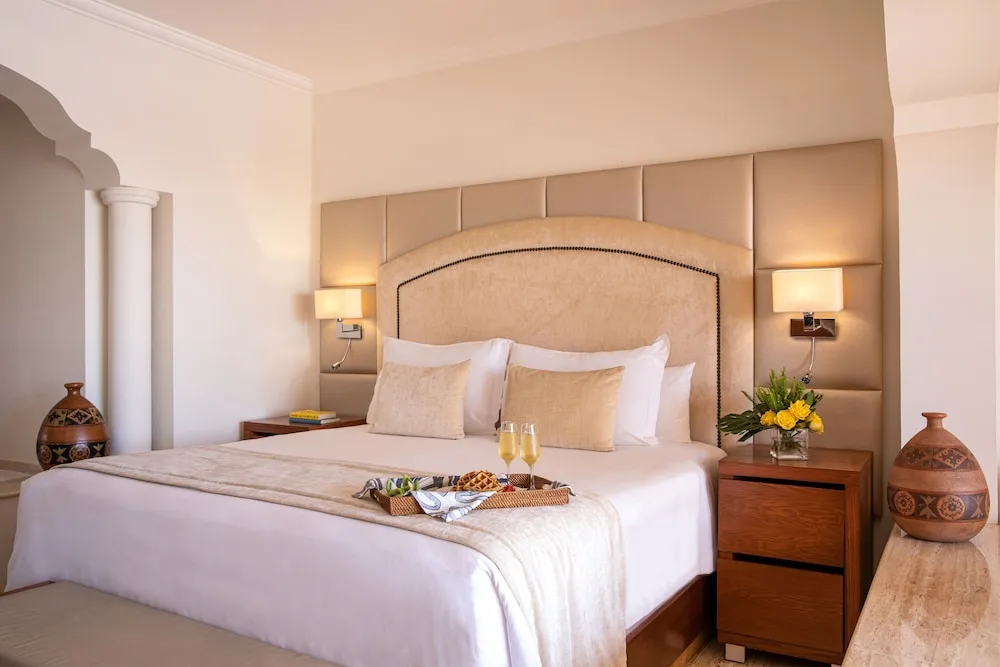 King bed guest room with tray service and bedside flowers at Excellence Riviera Cancun.
