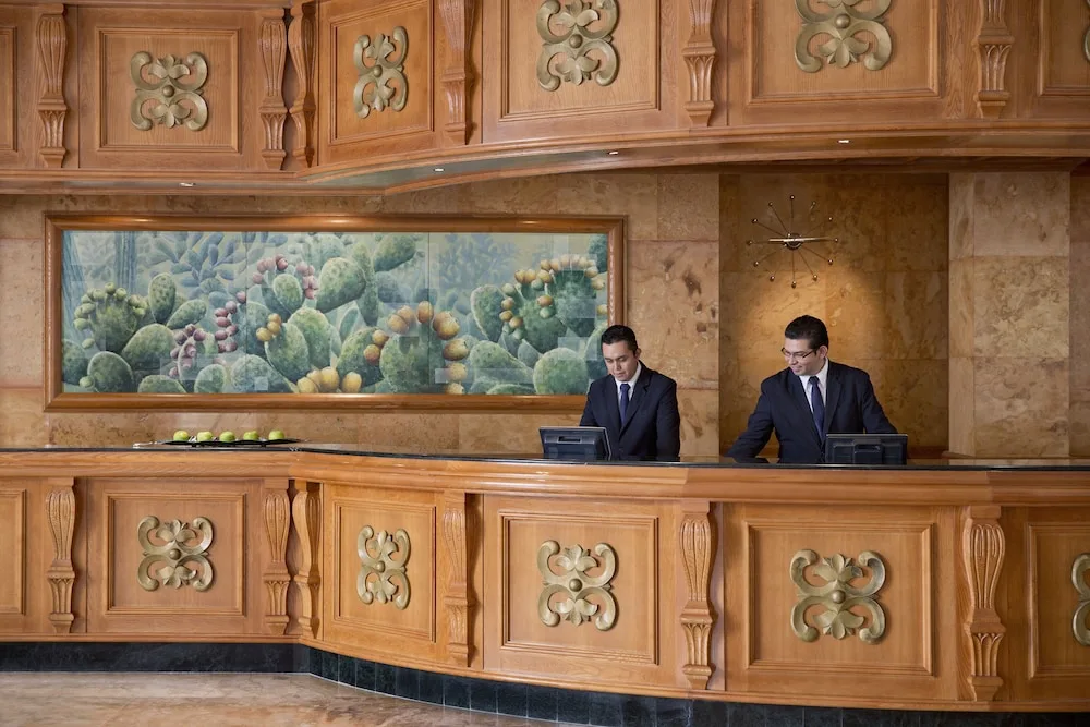 Lobby reception desk with staff and carved wood panels at Excellence Riviera Cancun.